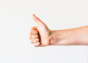 persons right hand doing thumbs up